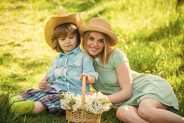 Nous sommes de la famille. vacances d'été. mère et enfant se détendent dans le parc. pique-nique sur herbe verte. fleur de printemps dans le panier. mère et fils en chapeau de paille. Joyeux jour de famille. fête des mères. petit garçon amour maman — Photo