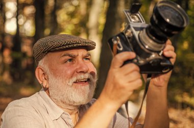 Elle ayarlar. Yaşlı adam doğada ateş eder. Dışarıdaki kameraman. Profesyonel fotoğrafçı. Manzara ve doğa fotoğrafı. Eski fotoğrafçı çekim yapıyor. Emeklilik hobisi. Deneyimli ve kalifiye fotoğrafçı.