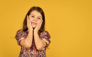 Kıymetli yüz. Çocuk sevgiyle yanaklarını kaldırıyor. Sarı arka planda tatlı bir kız gülümsemesi. Çocukluk ve mutluluk kavramı. Neşeli yüzlü fotokopi odası olan çocuk. Mutlu çocuklar günü. Mutlu çocukluk