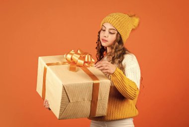 Entrika konsepti. Doğum günü kutlaması fikri. Doğum günü geleneği. Modaya uygun küçük kız örgü şapka ve kazak giyiyor. Doğum günü sürprizi. Güzel makyaj yüzü kıvırcık saç stili. Cömert hediye