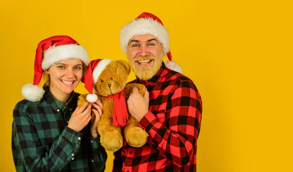 Familjesemester. Vi älskar julen. Älskande par gul bakgrund. Julen. Par förälskade i nallebjörn mjuk leksak njuta av jul semester. Familjtomtehattar. Underhållningsidéer för vuxna — Stockfoto