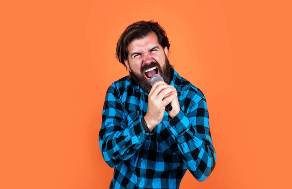 Брутальный бородатый мужчина рок певец, поющий песню в микрофоне в караоке, рок-музыка — стоковое фото