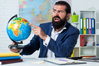 Eğil ve oyna. gayri resmi eğitim. Erkek öğrenci elinde haritayla okulda oturuyor. Sınavı geç. Konuyu öğrenmek. Coğrafyacı Kafası karışmış sakallı adam küreye bak. Coğrafya