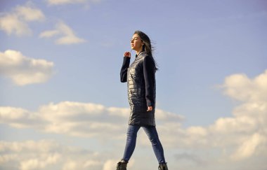 Hayalperest kız. Genç ve özgür bir kavram. Kıyafetlerinden daha fazlasını bekle. Kadınlar açık havada havadan hoşlanır. Güzellik ve moda. Yalnız yürüyorum. Mavi gökyüzü arka planında bir kadın. Kış tatili Uzun ceket.