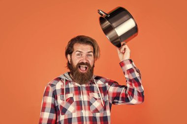 Restorana hoş geldin. İsimsiz dökme demir pişirme kabı. Yapışkan olmayan kaplamalı politetrafluoretilen teflon. Sağlıklı yemek pişirmek. Kareli gömlekli profesyonel aşçı. Sakallı koca