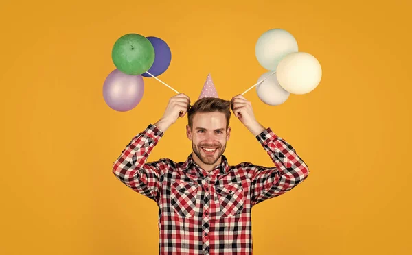 Partygänger pur. Lustiger Mann mit Geburtstagskappe. Typen halten festliche Luftballons in der Hand. Frohe Feiertage. Zeit für Spaß und Geschenke. Alles Gute zum Geburtstag oder Jubiläum. Freude und Heiterkeit — Stockfoto