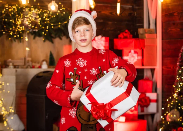 Noel Baba şapkalı çocuk evde iyi eğlenceler. Herkese mutlu noeller. Xmas hediyesi var. En iyi kış tatili. Mutlu genç yeni yıl partisini kutluyor. Kırmızı rengeyiği süveterli küçük çocuk. — Stok fotoğraf