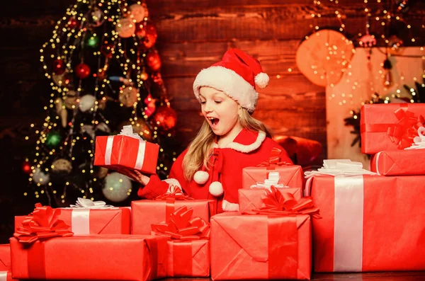 De Kerstman bracht me cadeaus. Kind blij opgewonden meisje vinden geschenken in de buurt van kerstboom. Geluk en vreugde. Vrolijk kerstfeest. Gelukkige kindertijd concept. Kind dragen santa hoed houden verpakt kerst geschenkdoos — Stockfoto