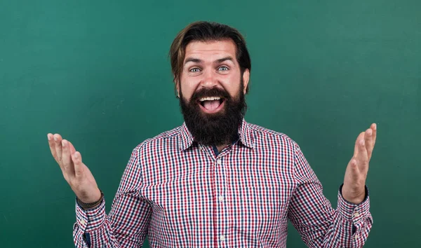 Homem barbudo brutal usar camisa xadrez casual e sorrindo. expressar emoções humanas positivas. hipster caucasiano sobre fundo verde. feliz professor maduro no fundo do quadro negro — Fotografia de Stock