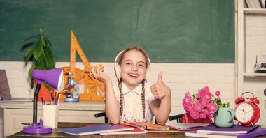 Ders aralarında atıştırmalık. Liseli kız masa başında tahtada oturuyor. Sağlıklı bir yaşam tarzı. Okul hayatı konsepti. Modern çocukluk. Okul tatili. Elma meyvesi yiyen küçük bir kız. Okulda çocuk öğrenci.