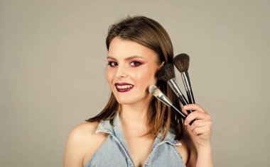 Modern moda tarzında makyaj. Cilt kozmetiği. Moda makyaj suratı. Uzun saçlı şehvetli bir kadın. Profesyonel makyaj fırçası olan seksi bir kadın. Güzellik kuaförü salonu. Ruj ve göz farı.