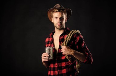 Her zaman nehrin yukarısındaki sürüden iç. Klasik tarz adam. Vahşi Batı eski kovboy. Kement ipli bir kovboy. Batı. Vahşi batı rodeosu. Siyah şapkalı adam. Çiftlikte kareli gömlek