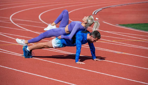 Treinamento de casal fitness esporte juntos ficar na prancha e fazer empurrar para cima na pista de corridas de estádio ao ar livre vestindo sportswear, esporte e força — Fotografia de Stock