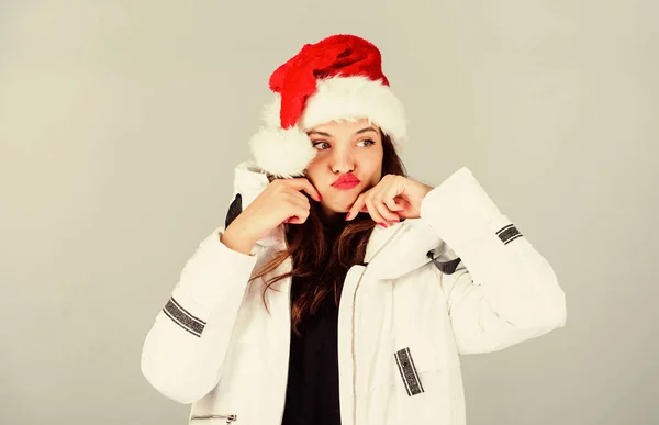 Várom a fagyos karácsonyi napokat. A lány fehér kabátot és télapó sapkát visel. A kabát extra szigeteléssel rendelkezik, hogy megvédje a testet az éles téli időjárástól. Fehér dzseki. Érzelmes női smink arc. Mikulás lány — Stock Fotó