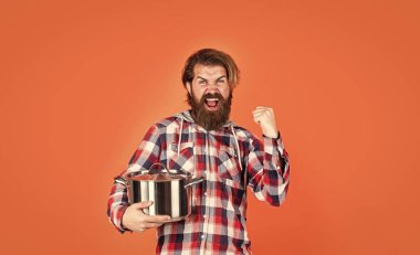 Sadece eğlenmek için. İsimsiz dökme demir pişirme kabı. Yapışkan olmayan kaplamalı politetrafluoretilen teflon. Sağlıklı yemek pişirmek. Kareli gömlekli profesyonel aşçı. Sakallı koca. Restoran