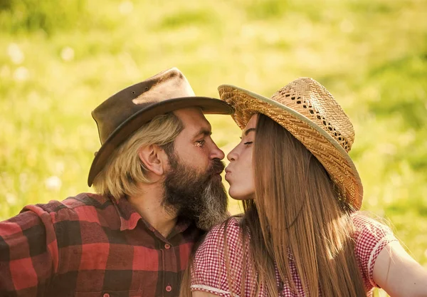 Amor y armonía. Vaquero barbudo con sombrero besando a su adorable novia. Pareja enamorada. Un beso romántico. Felices propietarios de ranchos. Casado y feliz. Gente rústica enamorada. Sentimientos verdaderos. Disfrutando de la vida — Foto de Stock