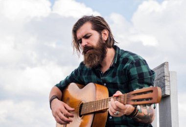 Popüler ol. Müzisyen müzisyen. müzik teli enstrümanı. Olgun karizmatik erkek gitarist. Sakallı ve bıyıklı adam gitar çalıyor. Kareli gömlekli sakallı adam şarkı söylüyor.