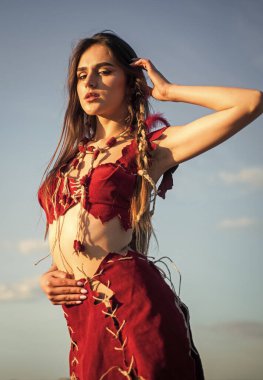 Köklerine geri dön. Ezoterizm ve okültizm. Vahşi ve tehlikeli. Ruhsal gelişim. Deri elbiseli bir kadın gökyüzü arka planı. Etnik kabile kavramı. Seksi kızmış. Kabile kıyafetleri. Kabile kültürü
