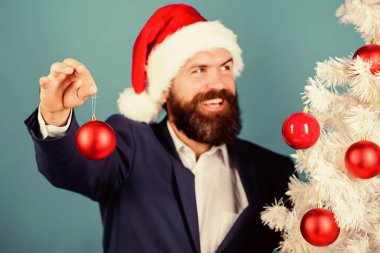 Noel Baba Noel balosu süslemesi. İş ve Noel konsepti. İş adamı size Noel hazırlıklarına katılmanızı teklif ediyor. Özel Noel teklifi. Sakallı hippi adam resmi takım elbise ve Noel Baba şapkası giyer.