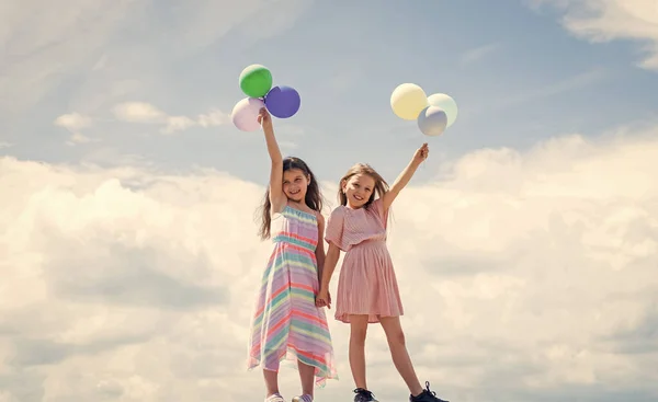 Dos hermanas sostienen globo de fiesta. Feliz infancia. vacaciones de verano. Las niñas pequeñas abrazan. amor y apoyo. concepto de hermandad y amistad. tiempo de vinculación familiar. mejores amigos con globo — Foto de Stock