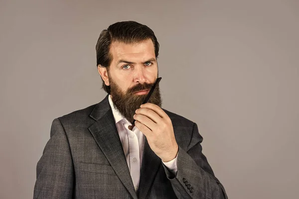 Hipster maduro con barba. brutal hipster caucásico con bigote. Cuidado de peluquero masculino. El hombre barbudo sostiene el cepillo de pelo. Cuidado del cabello y la barba. Un hombre brutal, seguro y guapo. cuidado facial —  Fotos de Stock