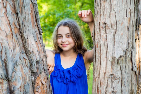Uzun kıvırcık saçlı bir kız ağaç gövdesine yaslanmış, yaz kampında. — Stok fotoğraf