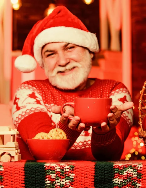 Зимние праздники. Горячий напиток. Рождественский рецепт какао. Гарланд освещает уютную атмосферу. Чувствую себя как дома. Дед Мороз пьет чай. Празднование Нового года. Дедушка с кружкой — стоковое фото