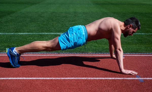 Athletischer Mann macht Liegestütze in Planke im Freiluftstadion, Sport — Stockfoto