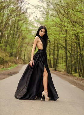 Seksi kız yol boyunca yürür. Dolaşma arzusu. Şık makyaj ve saç. Zarif elbiseli manken. Tepeden tırnağa. Şehvetli bir kızın moda görünüşü. Yaz tatili. Her yönden zarafet