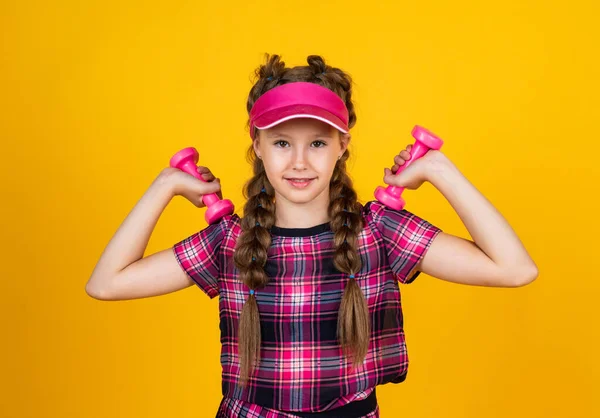 Güçlü ol. Genç kız eğitimi. Fitness 'e adanmıştır. Spor aletleri ve ekipmanlar. Sağlıklı ve aktif bir yaşam tarzı. Enerji dolu. Mutlu çocukluk. Şapkalı çocuk halterleri tutuyor. Dambılı çocuk — Stok fotoğraf