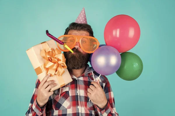 Ihre Bestellung ist fertig. Brutaler Mann auf Party. Lustiger Mann mit Geburtstagsmütze. Frohe Feiertage. Partygänger drehen durch. Spaß mit Luftballons. Jubiläum vorzubereiten. Eventmanager mit Geschenkbox — Stockfoto