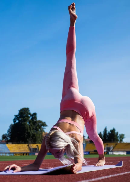Elastyczna kobieta rozciągająca się na stadionie w odzieży sportowej, pilates — Zdjęcie stockowe