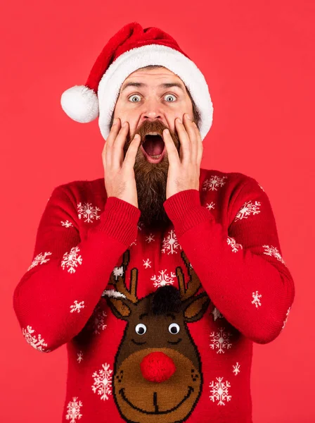 Hombre sorprendido con barba en sombrero de Santa Claus. hipster barbudo en jersey de Navidad. fiesta de invierno. compras en línea de Navidad. brutal hombre de fondo rojo. chico maduro celebrar año nuevo —  Fotos de Stock