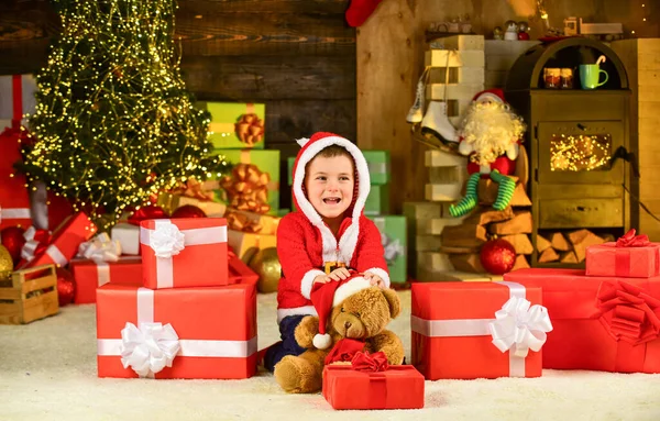 What is inside. small boy excited with present. kid hold decorative ball. bear toy gift for at xmas. merry christmas. happy new year. happy child santa hat. son ready to celebrate winter holidays — Stock Photo, Image