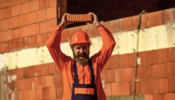 Lightweight brick made from expanded clay aggregate. Element in masonry construction. Builder hold brick. Bearded man wear hard hat at construction site. Brick building material used to make walls — Stock Image Lightweight brick made from expanded clay aggregate. Element in masonry construction. Builder hold brick. Bearded man wear hard hat at construction site. Brick building material used to make walls Stock Picture