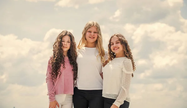 Three girls on sky background. concept of female friendship. sisterhood and family. best friends together at school. back to school. happy childhood. cheerful small kids — Stock Photo, Image