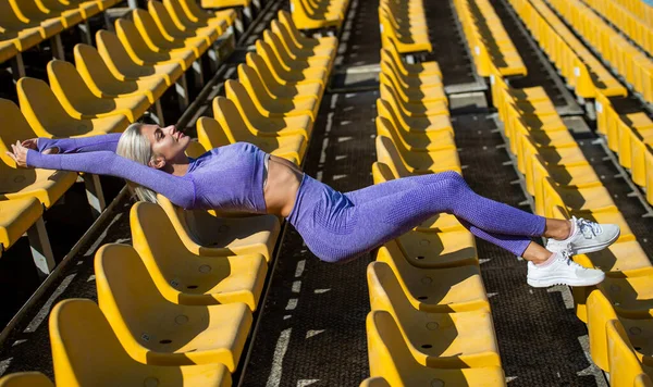 Vrouw met sexy fitness lichaam in sportkleding ontspannen op het stadion, fit lichaam — Stockfoto