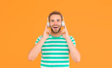 İşte ben buna müzik derim. Mutlu adam sarı arka planda müzik dinliyor. Yakışıklı adam kulaklıkla müzik çalmaktan hoşlanıyor. Modern hayat. Yeni teknoloji. Eğlence ve eğlence. Müzikte kaybolmuş