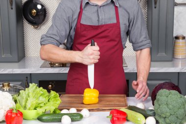 Eldeki seramik bıçak, gemide sarı biberli sebze kesimi.