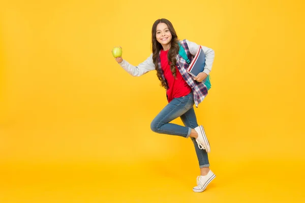 Hurry up to take snack break. Energetic child run holding apple and books. School break. Nutrition education. Brain food. Healthy eating and snacking. Lunch time. Diet and dieting, copy space