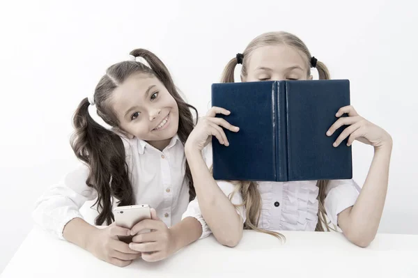 Ouderwets tegen modern. Schoolmeisje houden mobiele telefoon moderne smartphone, terwijl haar vriend genieten van het oude boek als analoge data-opslag. Technologie tegen ervaring. Nieuwe generatie educatieve eisen — Stockfoto