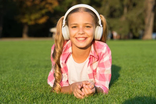 Muzyka pomoże ci odpocząć. Szczęśliwy dzieciak słucha muzyki leżącej na zielonej trawie. Zabawa i rozrywka. Zajęcia rekreacyjne. Nowoczesne życie i technologia. Odpręż się. Wakacje — Zdjęcie stockowe