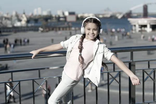 Deja que la música te lleve lejos. Un niño pequeño escucha música al aire libre. Feliz niñita. Pequeño fan de la música. Chica feliz usar auriculares. Golpe de la calle — Foto de Stock