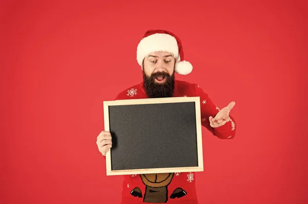 Ez hihetetlen. Mikulás kalap hirdetéssel. Chalkboard az információért. Ember tartsa üres tábla másolási hely. Guy Santa Claus piros háttér. Téli bejelentés. Téli esemény. Téli ünnepek — Stock Fotó