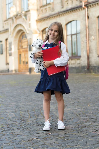 Předškolní výchova. Dítě ve školce venku. Dítě drží psí hračku a knížky. Playschool a školka. V mimoškolním klubu. Přinášíme hru k učení — Stock fotografie