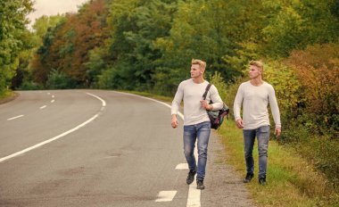 Boş yolda otostop çekerek. Otostop yaparak. Yolculuk. Yolculuk tutkusu konsepti. Arkadaşlarla yürüyüş yapmak iyidir. Kendilerini bulmaya gittiler. Seyahat ve otostop. Yol boyunca yürüyen ikizler