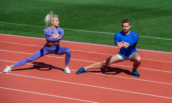 Fitness homem esporte e mulher aquecimento e alongamento juntos na pista de corrida estádio ao ar livre vestindo sportswear, treinador — Fotografia de Stock