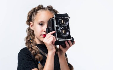 Ateş et. Retro kamera. Mutlu çocukluk. Çocuğun şık bir görünüşü var. Modern hayatta fotoğrafçılık. Eski moda fotoğraf makinesi olan çocuk beyaza izole edilmiş. Eski teknoloji. Genç kız fotoğraf çekiyor.
