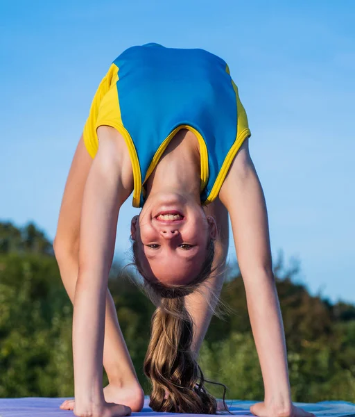 Adolescente chica desgaste ropa deportiva para el entrenamiento estiramiento en el cielo fondo, flexibilidad — Foto de Stock