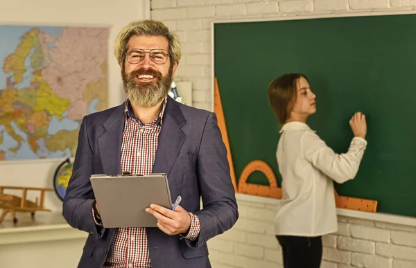 Šťastný učitel a dítě ve třídě. Změna služby. vousatý muž si dělá poznámky do schránky. Holčička píše odpověď na tabuli. zkouška nebo lekce. Zpátky do školy. moderní vzdělávací koncept — Stock fotografie